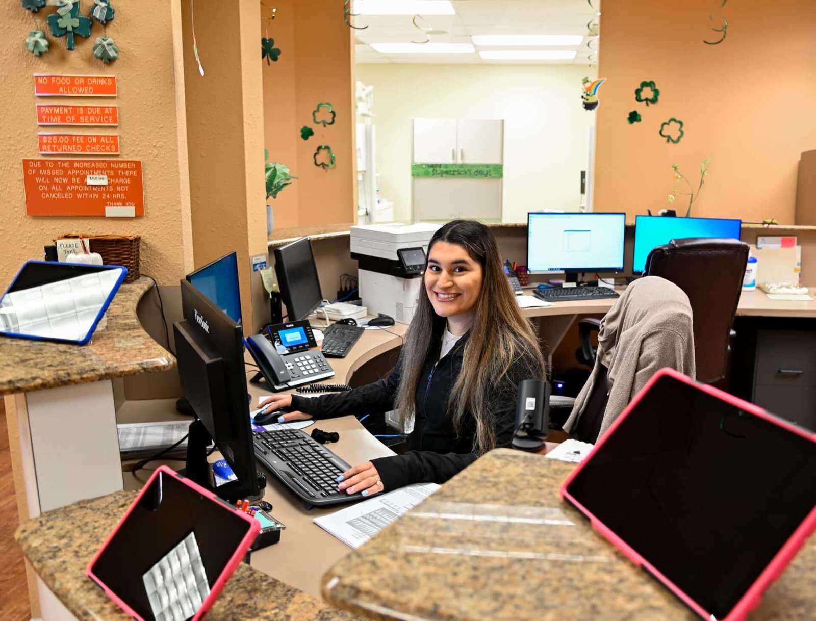 Longhorn Dental employee at front desk smiling at camera.