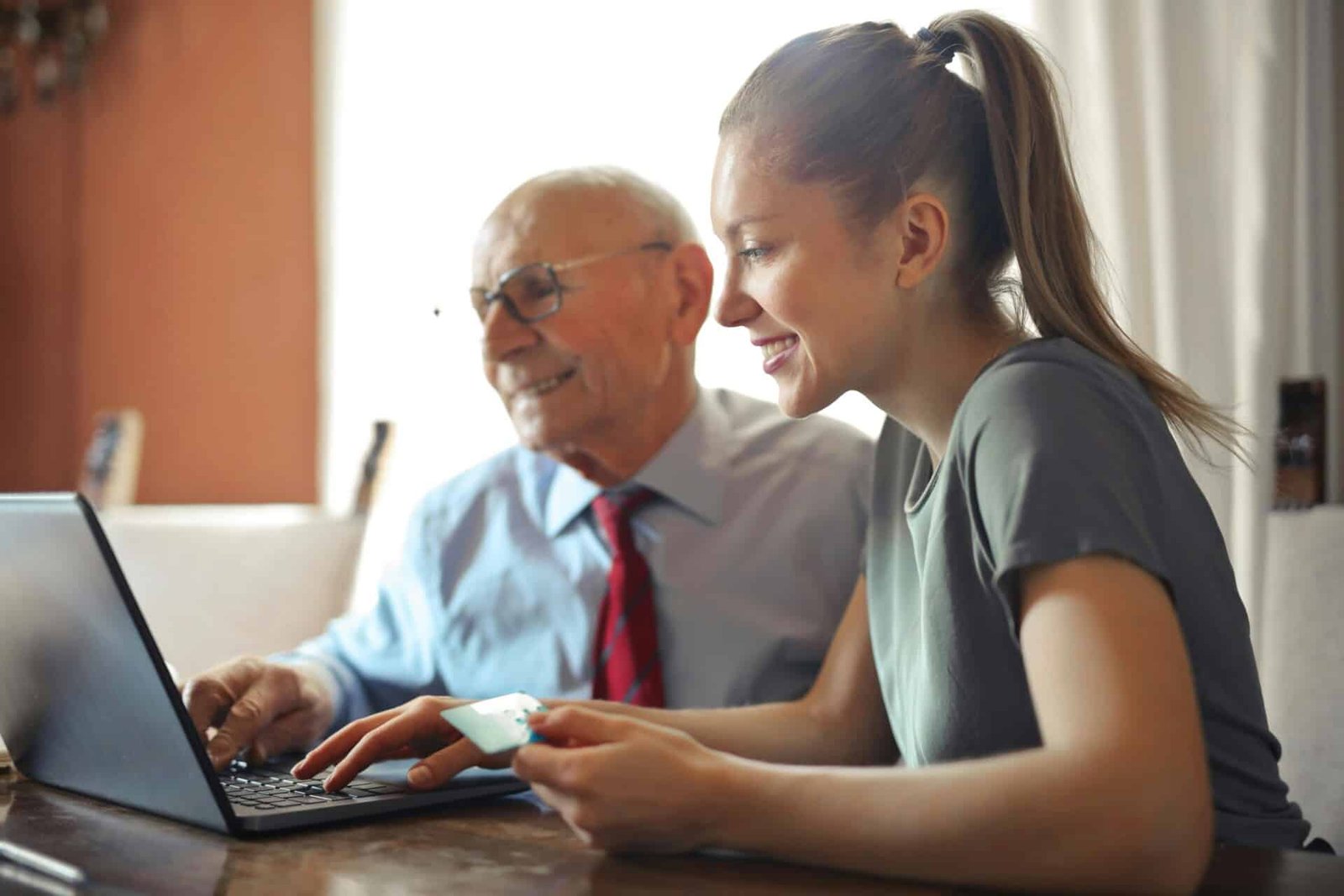 A younger woman and older man looking at a laptop.