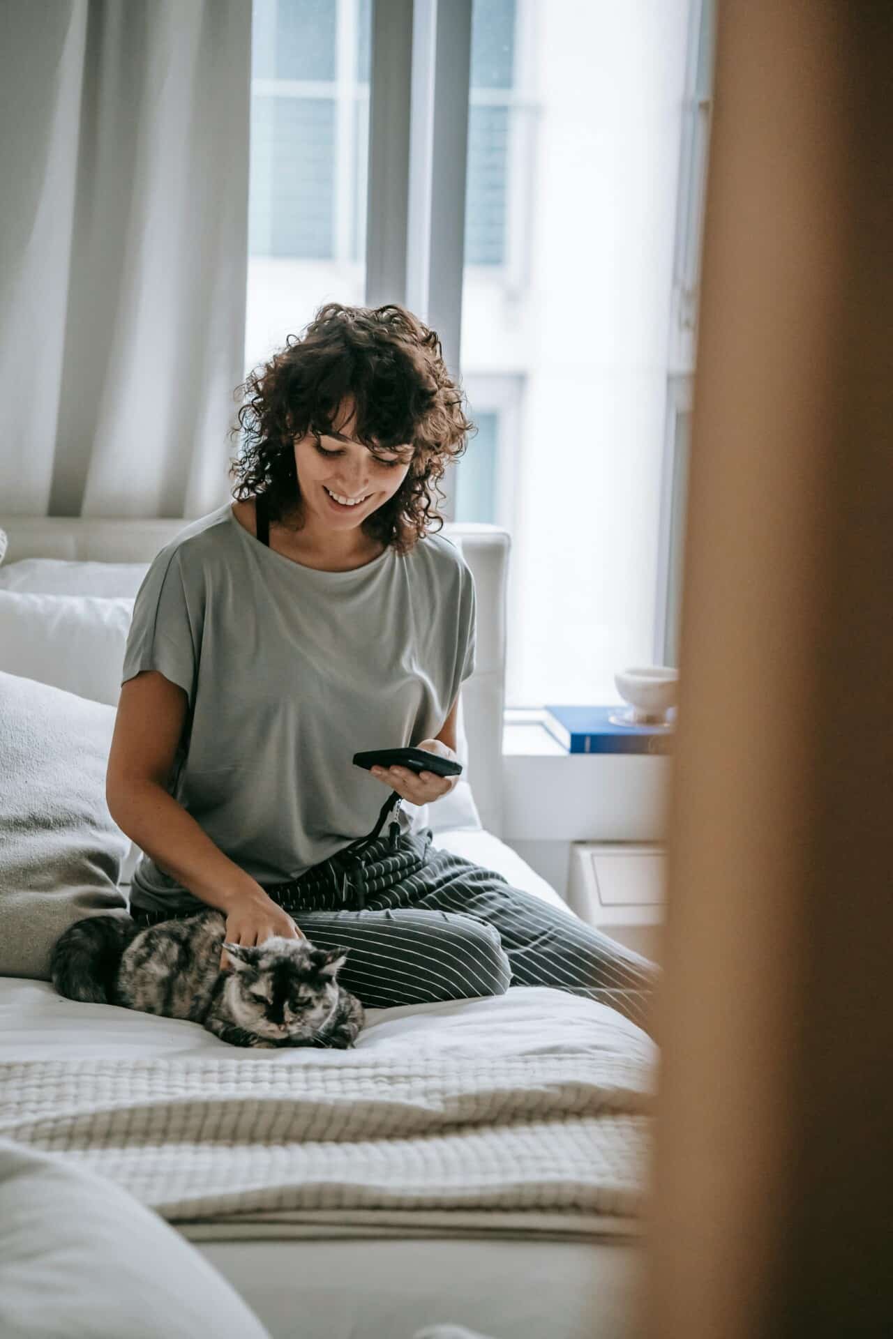A woman looking at her phone with a cat.